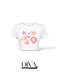 White seashell graphic crop t-shirt with pink starfish and shell print for vacation and summer birthday outfits.