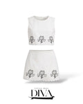 White two-piece set featuring embroidered floral crop top and matching mini skirt with scalloped hem